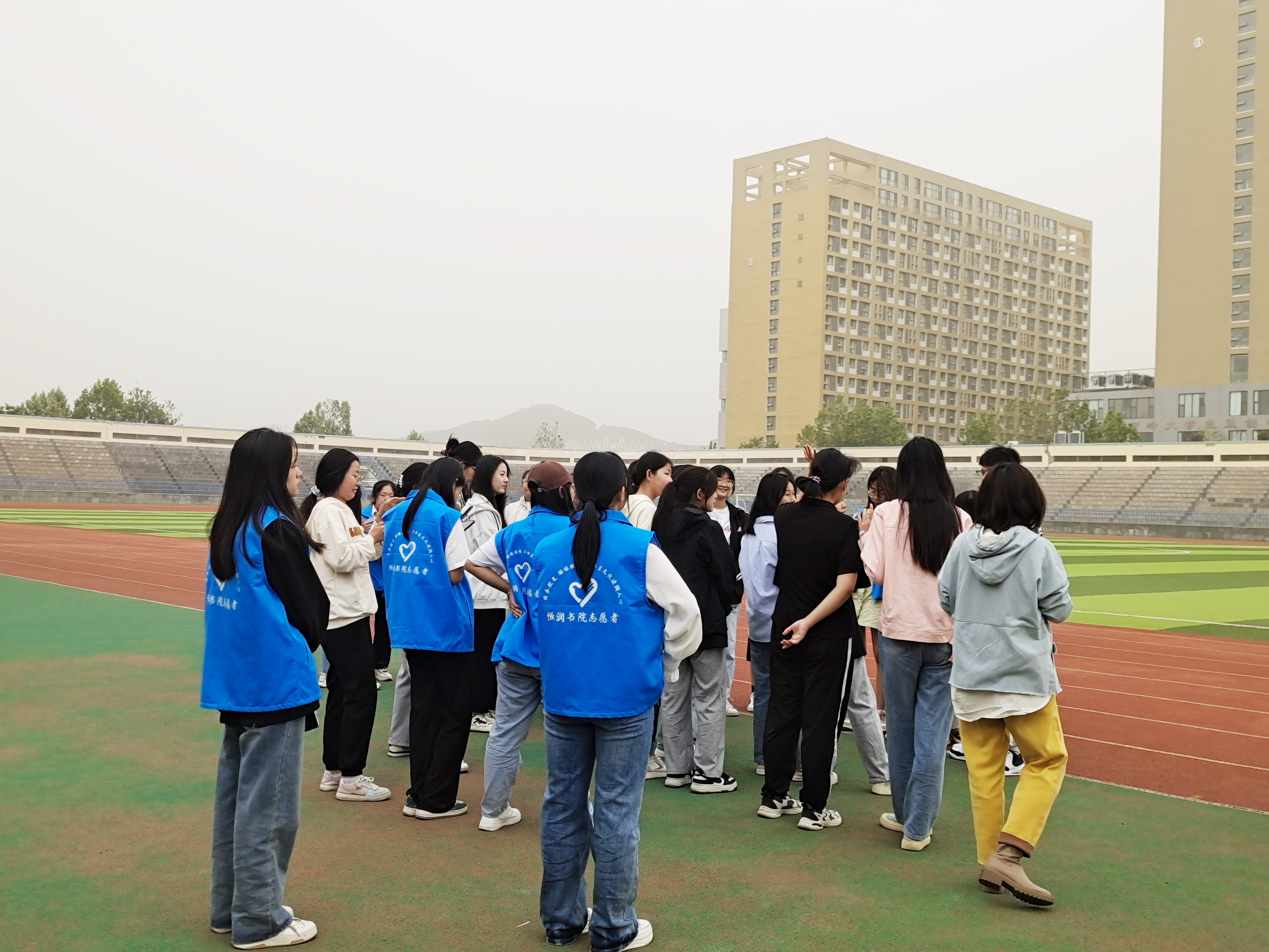 5月21日，青岛恒星科技学院恒润书院首届趣味运动会在恒星体育场热闹举行，运动项目有“二人三足”、“踩气球”、“寻找丢失的许愿瓶”等，参赛学生们全心投入，尽情释放，尽享运动乐趣。图为恒润书院志愿者现场服务。