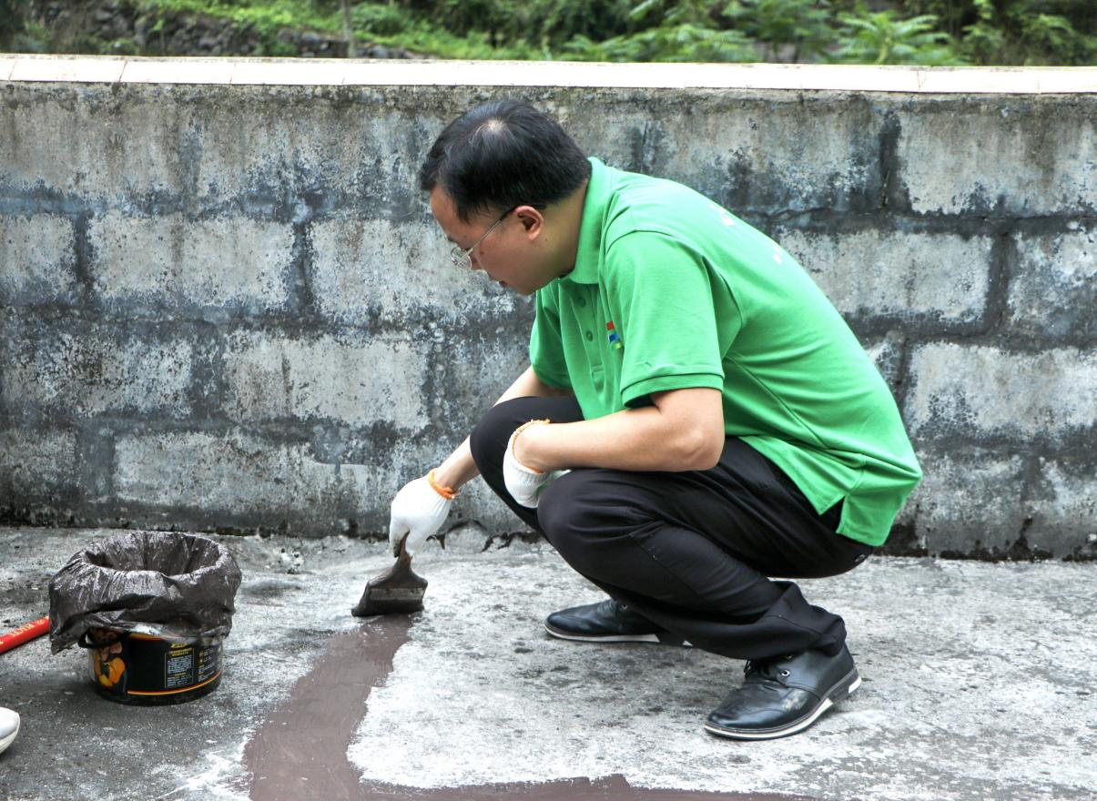 实践团成员在裂缝处涂抹防水涂料2.png