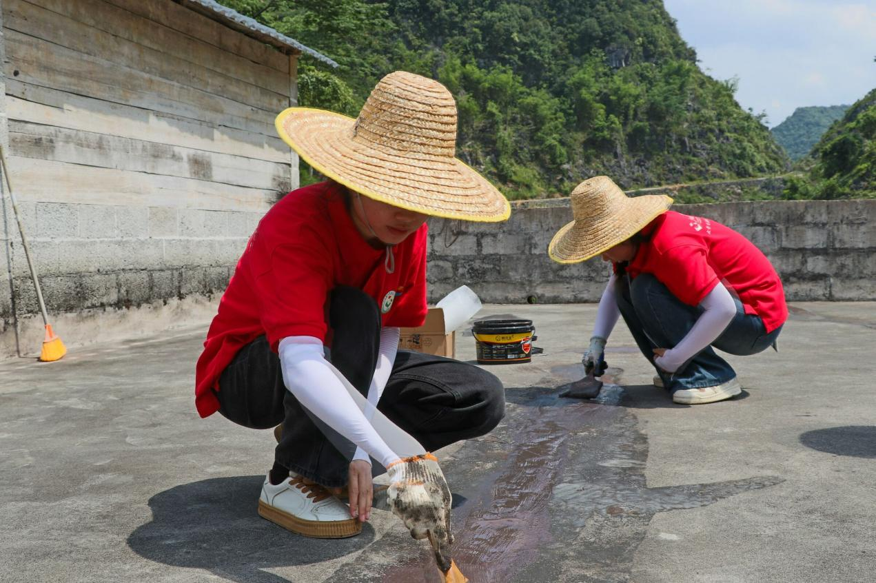 实践团成员在裂缝处涂抹防水涂料3.png